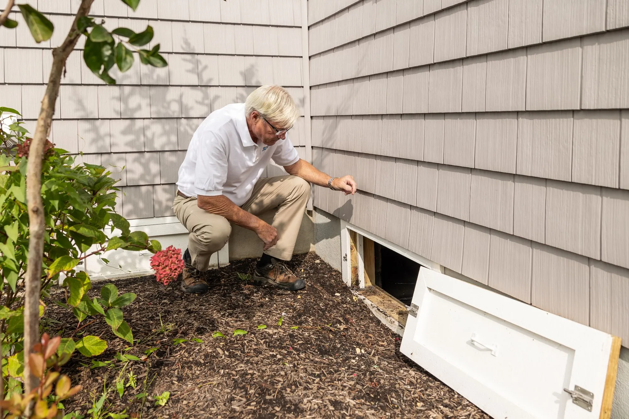A worker checking cladding low down on the side of a house