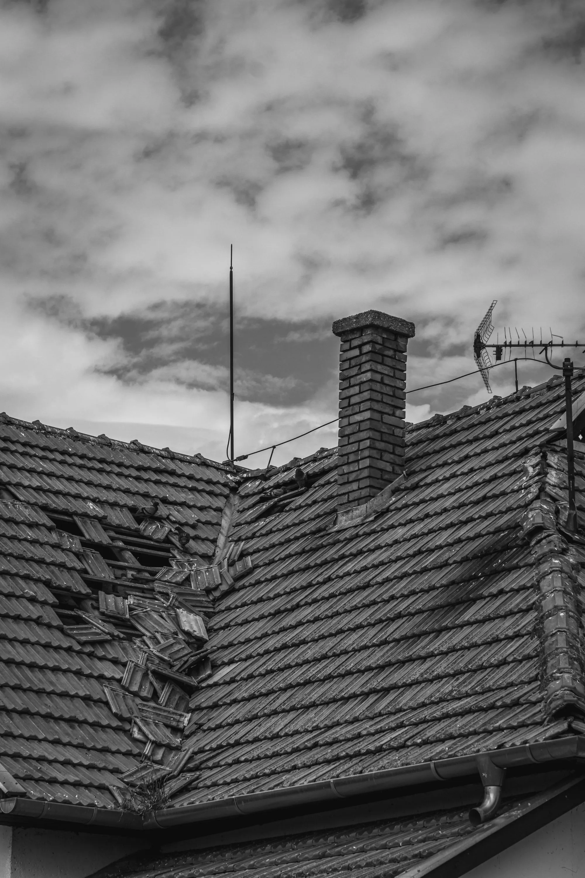 A roof slope with broken and displaced covering after a storm